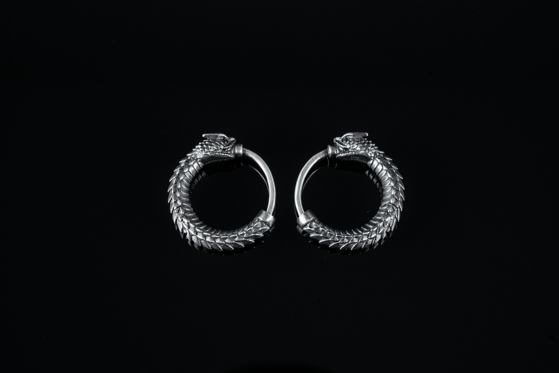 a pair of silver hoop earrings on a black background